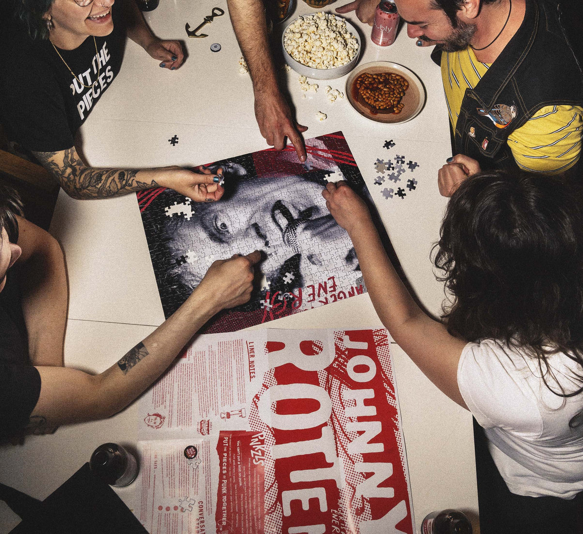 Overhead shot of people at a table, laughing and putting puzzle together